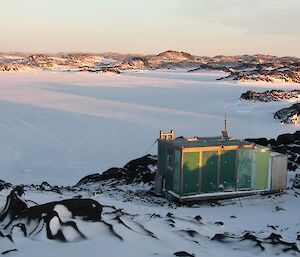 The green cube of Bandits hut sits on an island looking down on the sea-ice of Tryne Fjord.