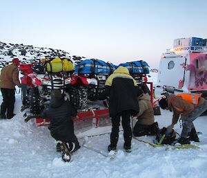 The quad bikes are put on a sled trailer and towed home.