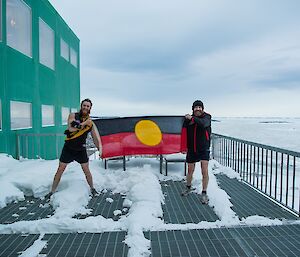 Bryce and Fitzy are holding the aboriginal flag in front on the Living Quarters building. Bryce is in Richmond gear while Fitzy is wearing Essendon gear.