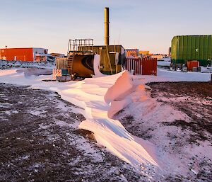 Snow sculptured by the wind. A pointed blizz tail, which looks architectural, is downwind of the incinerator building.