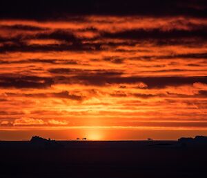 A cloudy orange sunset over the icebergs.