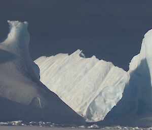 An image of three icebergs, all on different angles, looking like abstract art.