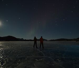 Bryce and Shoey are seen in silhouette against a night sky with a bright moon.