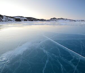 The frozen ice of Crooked Lake in twilight. Lots of cracks are seen in the beautiful clear ice.