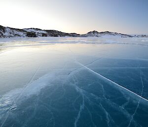 The frozen ice of Crooked Lake in twilight. Lots of cracks are seen in the beautiful clear ice.