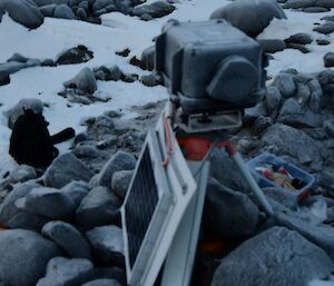 A remote penguin monitoring camera, set up on Gardner Island. It looks like a plastic case on a tripod with a solar panel at its feet.