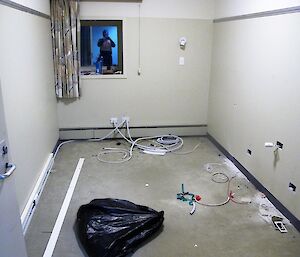 The room now has many holes and cables hanging out through the walls, indicating that the electrical work is almost done.