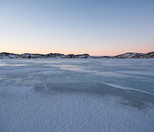 Driving over sea ice towards Ellis Fjord. The dark Vestfold Hills are seen to the side of the fjord.