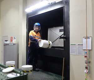 Fitzy pouring a bucket of wet waste from the kitchen into the macerator at the waste water treatment plant.
