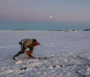 Jock chainsawing squares into the ice to aid with removal.