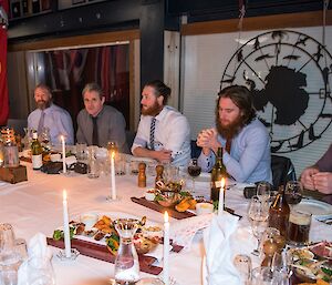 Everyone sitting at a table ready to eat entrees.
