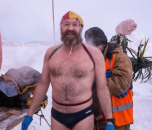 Fitzy standing outside on the ice in bathers post-swim.