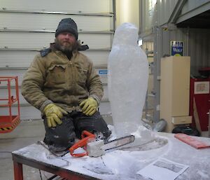 Jock in the boat shed, working on the penguin sculpture with a small chainsaw.