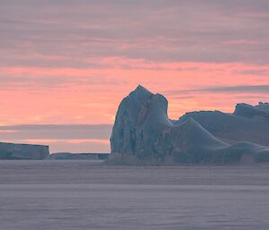 Bergs in civil twilight: soft pastel skies of pink and peach.