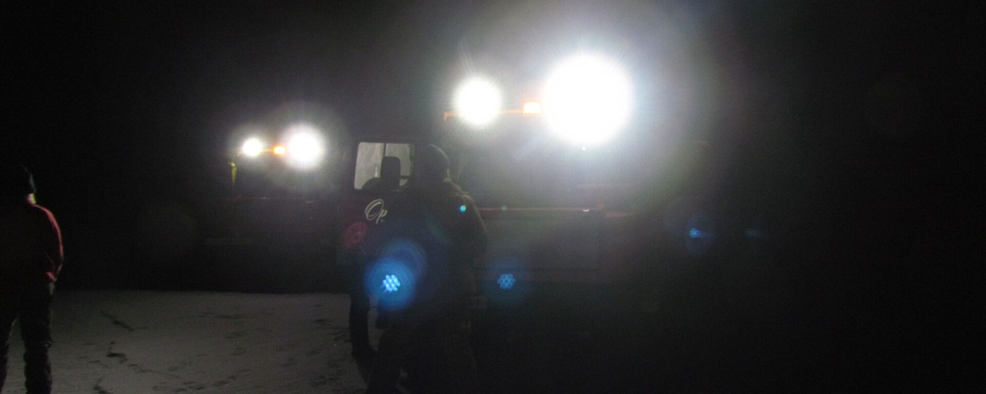 Two Hägg’s headlights reveal people standing on the sea-ice. This is early on in the trip, when it is dark and very cold.