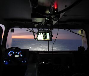 The view from the back seat of the Hägg, looking out the windscreen to the vast plateau in soft pastel light during civil twilight.