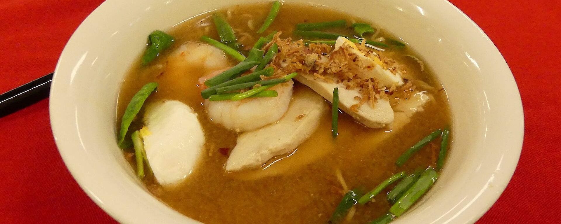 Delicious Japanese ramen dinner, in a bowl on a red table cloth.