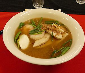 Delicious Japanese ramen dinner, in a bowl on a red table cloth.