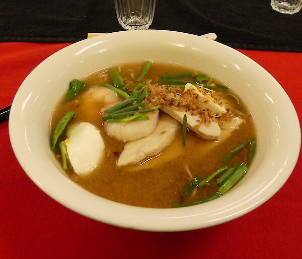 Delicious Japanese ramen dinner, in a bowl on a red table cloth.