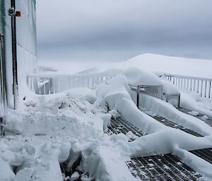 The snow accumulation outside the living quaters building following the blizzard. Note the snow dunes are as high as the deck!
