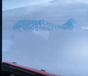 A iceberg with a corrugated texture is seen through the Hägg window.