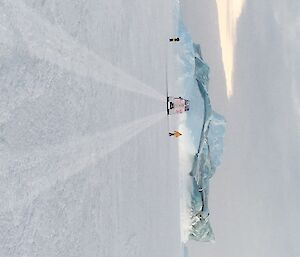 The Hägg is parked in front of a marbled jade berg. Two people are standing on the ice, either side of the Hägg admiring the view.