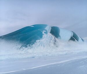 A beautiful ice berg that has a dark colour in contrast to others that are often quite light.