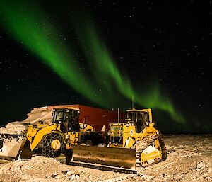 Auroras are seen behind the snow clearing machinery.