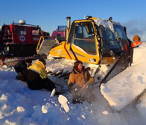 Expeditioners digging around the machinery buried in the snow.