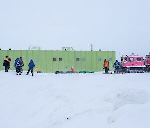 The Hägg is seen parked on the snow in front of the SMQ building. Ropes are strung out from the front of the vehicle as a rescue system. People are standing around working on the rope work.