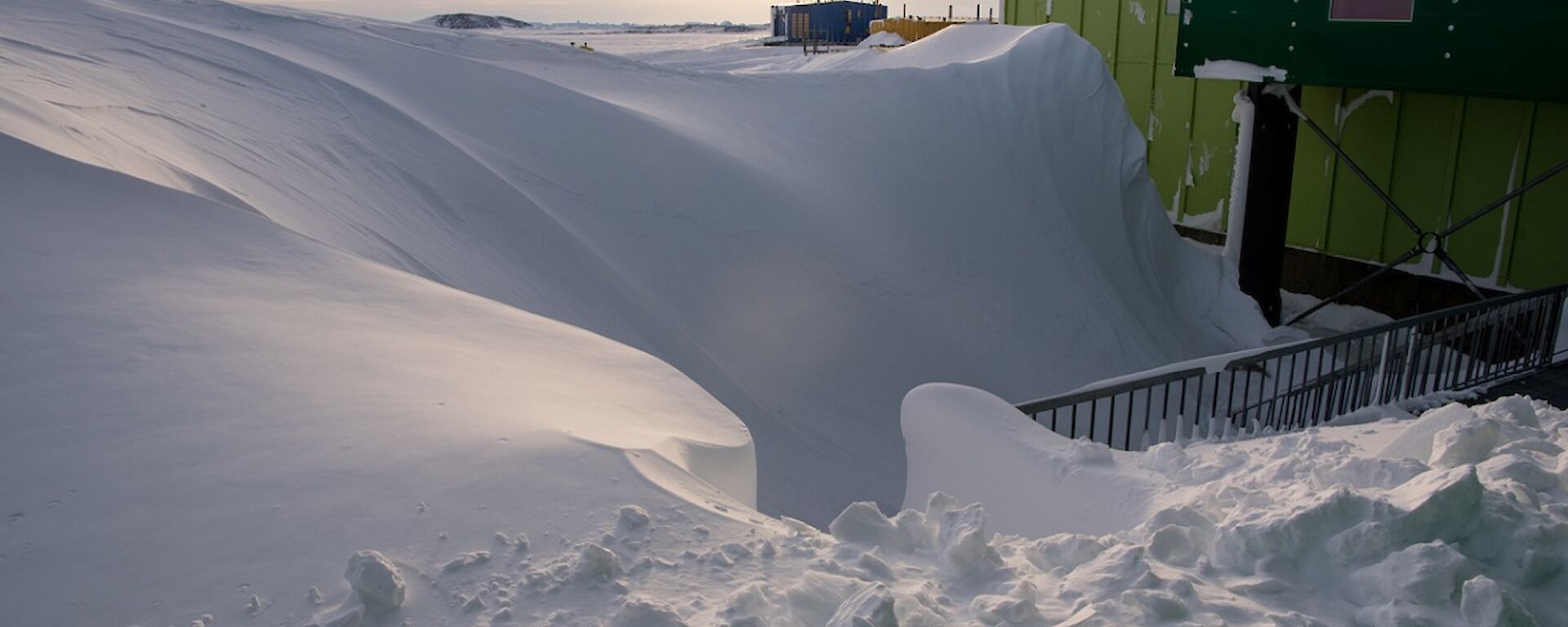 A massive snow dune exists in front of the living quarters building.
