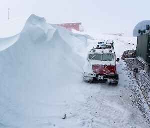 A blizz tail behind the living quarters, which is much higher than a vehicle parked near it.