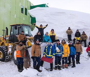 A group photo of the team, the excavator and the snow dune that is in front of the LQ.