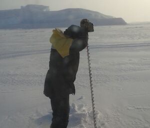 Rhys drilling a hole in the sea ice to enable ice thickness to be measured.