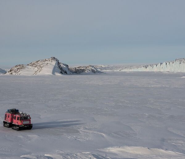 The pink Hägg, travelling in sunshine over sea ice down Crooked Fjord. The Sørsdal Glacier is seen to the right of the fjord.
