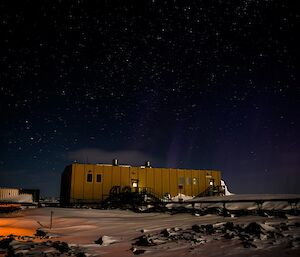 A building under a starry sky and weak aurora.