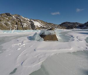 View of a frozen lake covered with some snow. The hills are in the background.