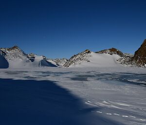 A beautiful frozen lake, with hills in the background.