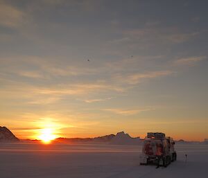 A summer sunset with a Hägg out on the sea ice and birds flying overhead.