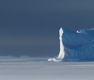 The sun finally peaks out and lights up the side of an berg.