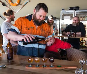 Marc (Brew master) is pouring five different coloured beers onto a sampling tray for those in the Bar to try for Oktoberfest.