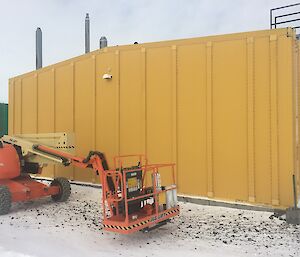 The elevated work platform alongside the yellow science building, getting ready to unblock the HVAC (heating venting and air conditioning) system located on the roof.