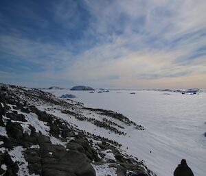 Jock’s silhouette is seen on the edge of an island with a penguin colony seen beyond him.