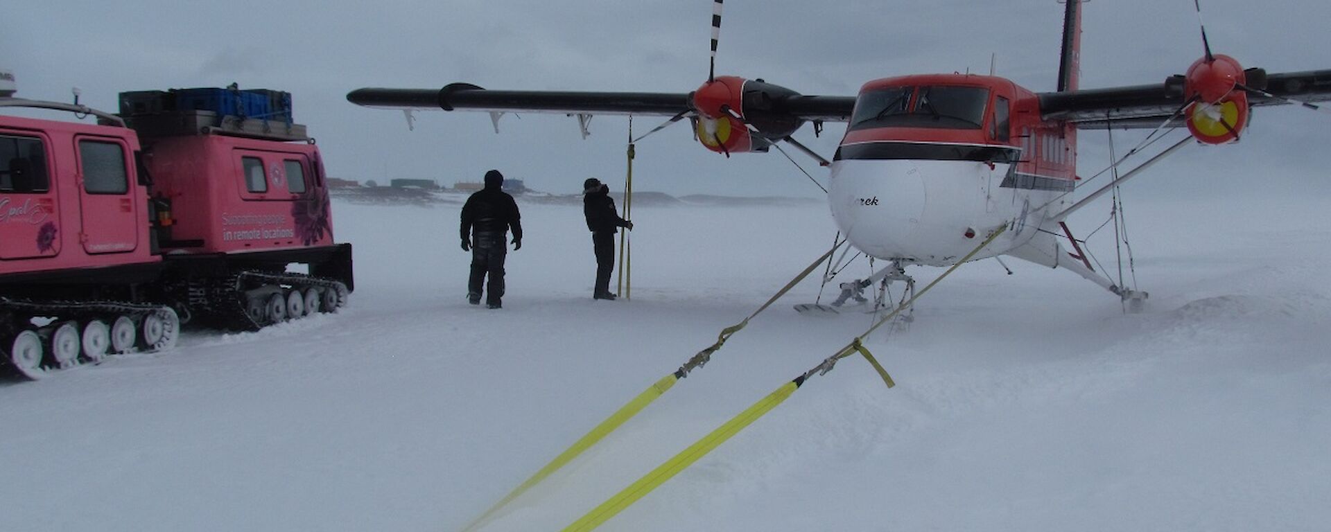 The pilots, Doug and Jeff, check the Twin Otter’s wing tie downs. Blizz covers the plane’s skis.