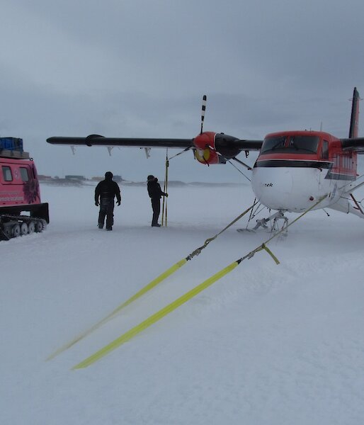 The pilots, Doug and Jeff, check the Twin Otter’s wing tie downs. Blizz covers the plane’s skis.