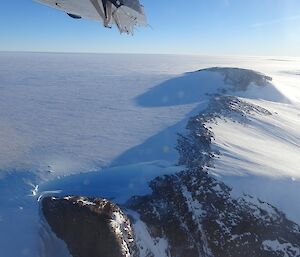 Photo taken of Mountain with blue sky and part of the air wing showing.