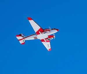 A red and white plane in a blue sky.