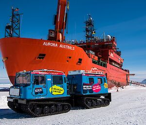 A blue tracked vehicle on the ice in front of the ship.