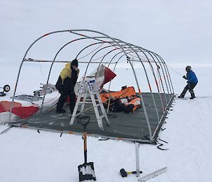 Two people erecting a tent.