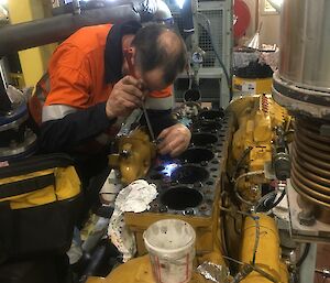 A mechanic works on an engine.